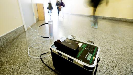 En alkoholtester står på gulvet i en gang, med folk som går forbi i bakgrunnen.