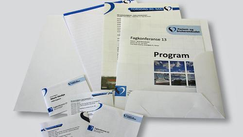 Dokumenter og brosjyrer fra et arrangement, inkludert program og visittkort i en bunke.