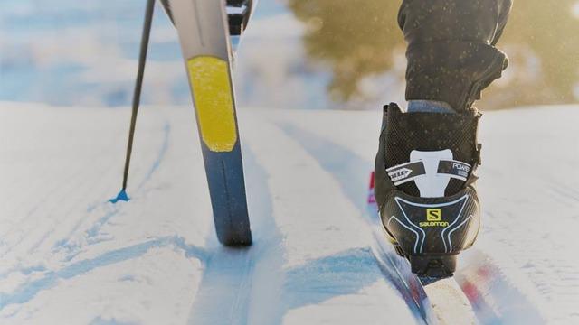 En person som går på langrenn med ski og spesialiserte skistøvler på snødekt terreng.
