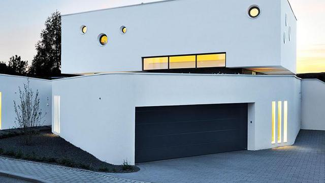 Moderne, hvit enebolig med runde vinduer og garasje, beliggende i et rolig nabolag.