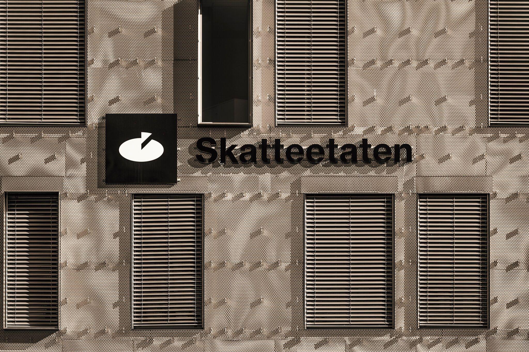 Bygning med Skatteetaten-skylt og vinduer med persienner i moderne design.