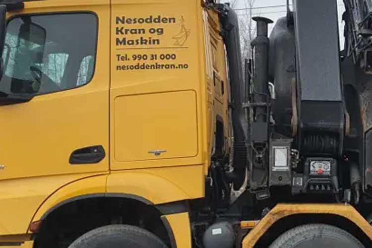 Gul lastebil med påskrift "Nesodden Kran og Maskin" og kontaktinformasjon på siden.