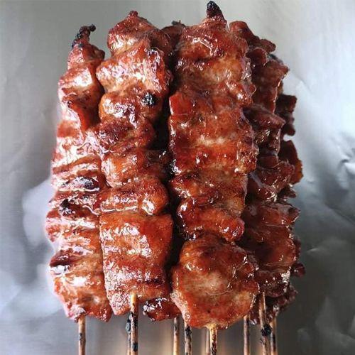 Grillspyd med saftig svinekjøtt, perfekt stekt og glassert, stablet på en tallerken.