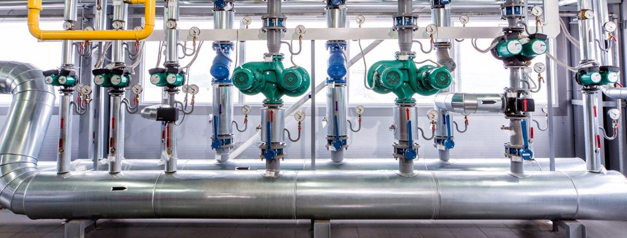 Rørledninger med grønne ventiler og metallkomponenter i et industrielt anlegg.