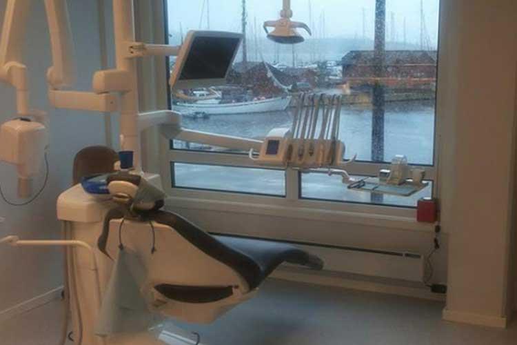 Tannlegekontor med moderne utstyr og utsikt over havnen med båter.