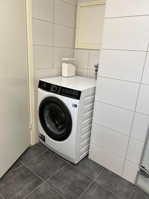 Vaskemaskin plassert i et rom med fliser på veggene og gulvet.