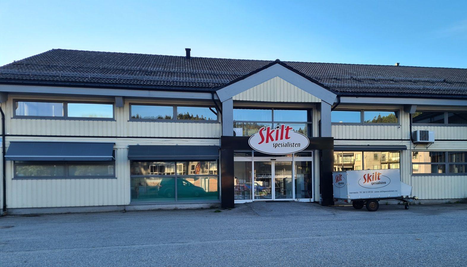 Bygning med skilt som viser navnet "Skite" og en tilhørende trailer foran inngangen.
