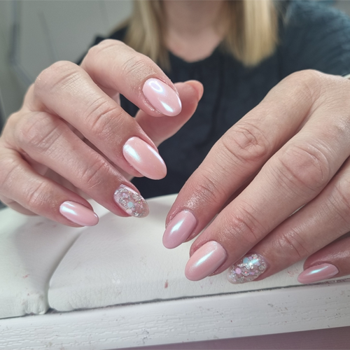 Hender med manikyr og rosa neglelakk, inkludert glitrende detaljer på noen negler.