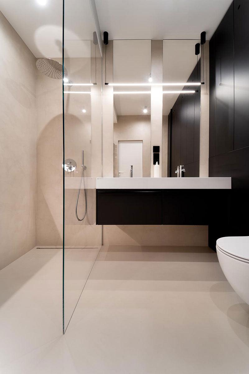 Moderne bad med glassdusj, svart skap, og minimalistisk design. Lys belysning og stilige detaljer.