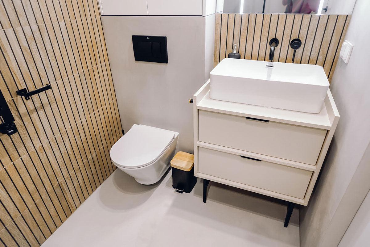 Moderne bad med veggmontert toalett, servant på skap og trepanel på veggene.