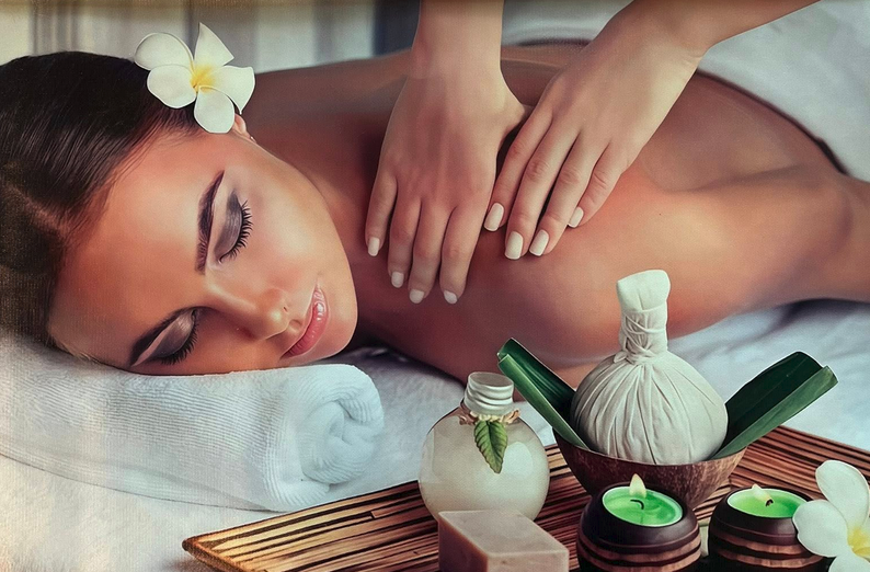 Kvinne som får massasje med aromatiske oljer, omgitt av stearinlys og spa-produkter på et trebrett.