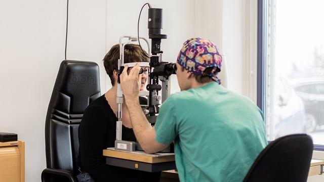 En optiker undersøker en pasients øyne med en spaltelampe i et moderne kontor.