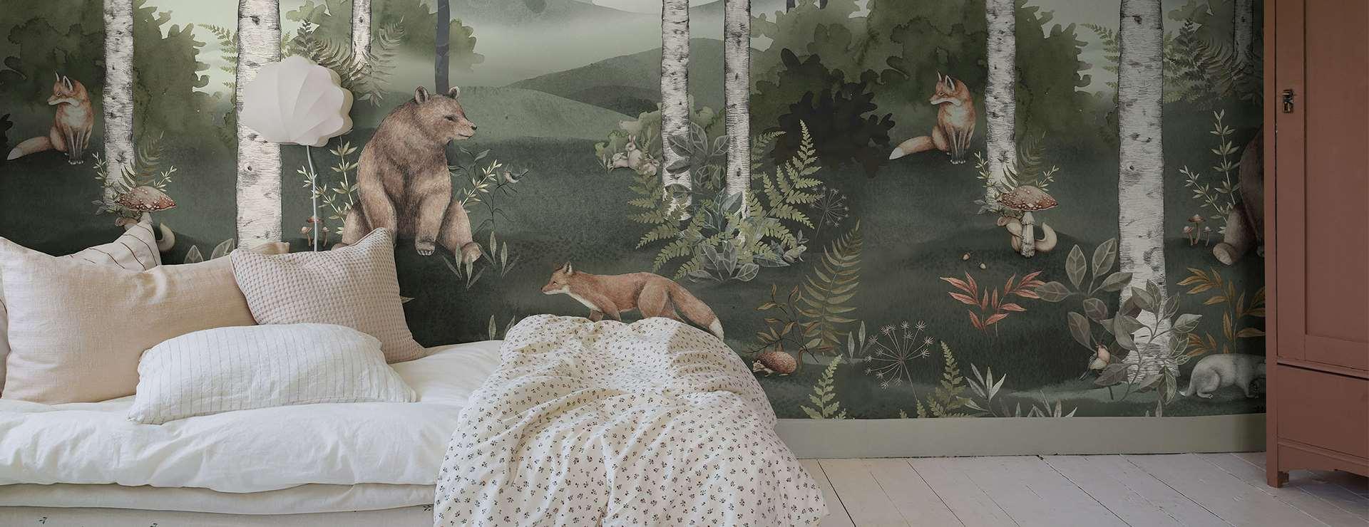 Soverom med en veggdekorasjon av bjørner og skog, myke puter og en seng med et lyst sengeteppe.
