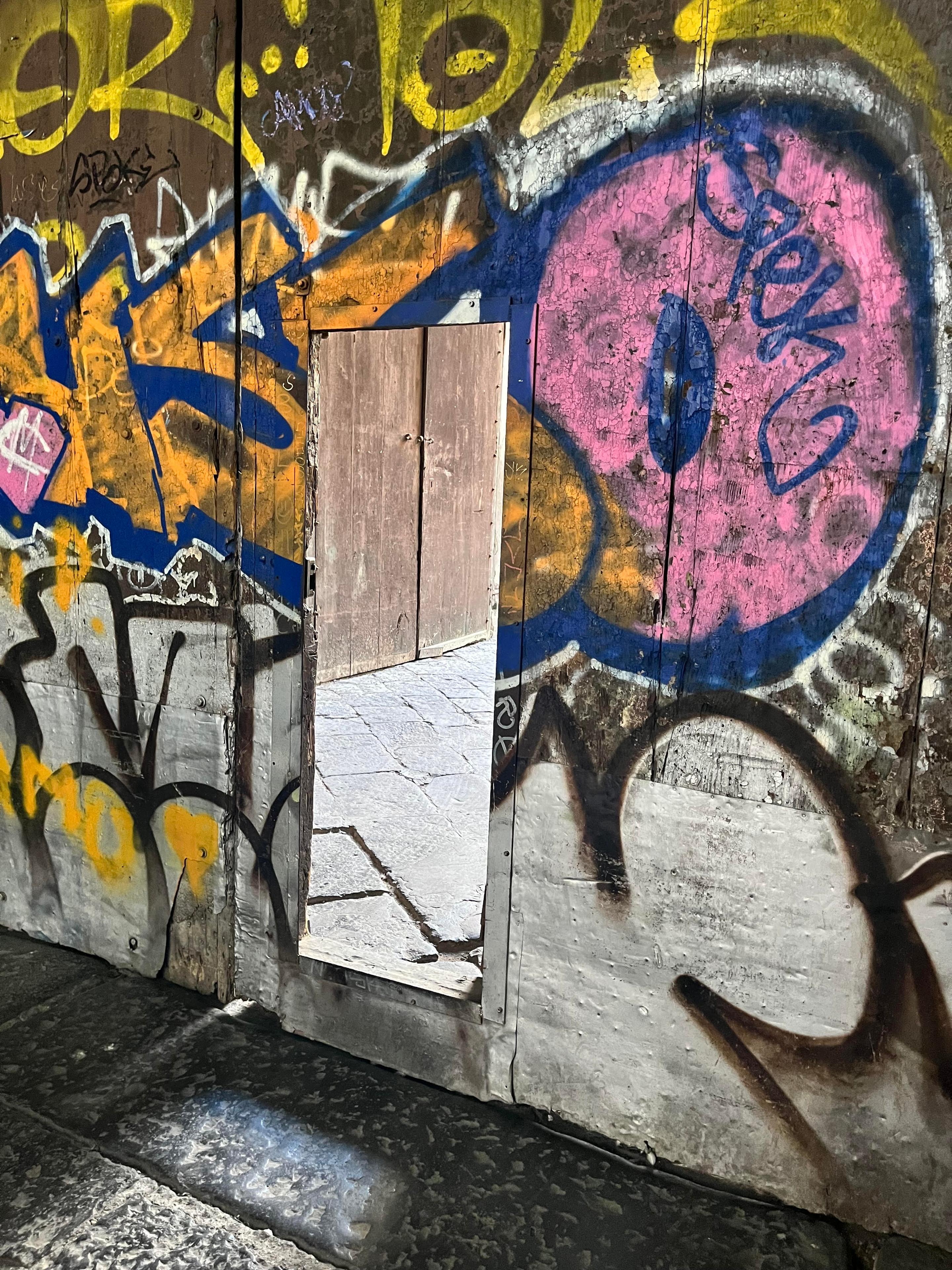 Speil på en vegg dekket av fargerik gatekunst og graffiti i en urban setting.