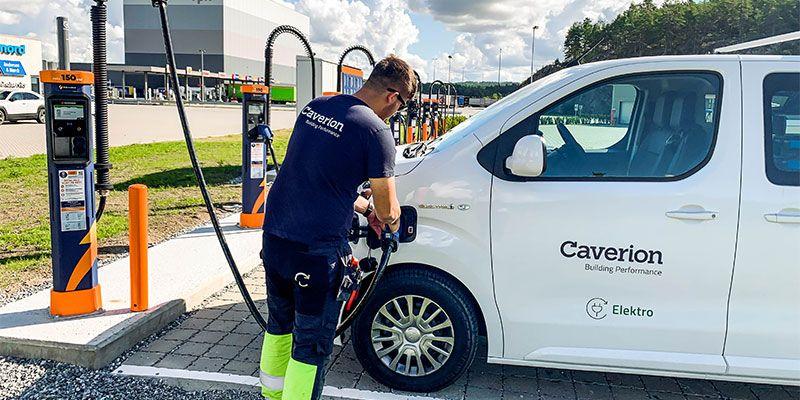 En mann fyller drivstoff på en Caverion-merket varebil ved en bensinstasjon.