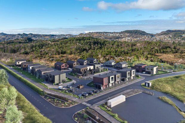 Moderne boliger i et nytt nabolag med grøntområder og veier, omgitt av skog og fjell.