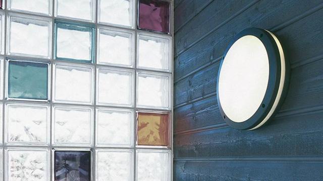 Rund taklampe på en vegg med farget glassblokker som slipper inn naturlig lys.