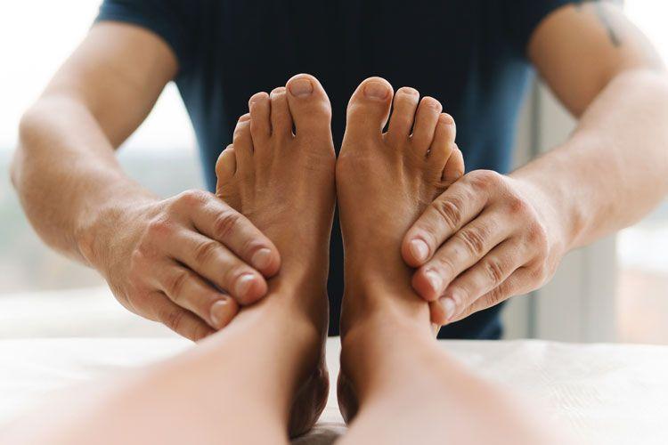 En person får fotmassasje av en terapeut med hender som masserer føttene.