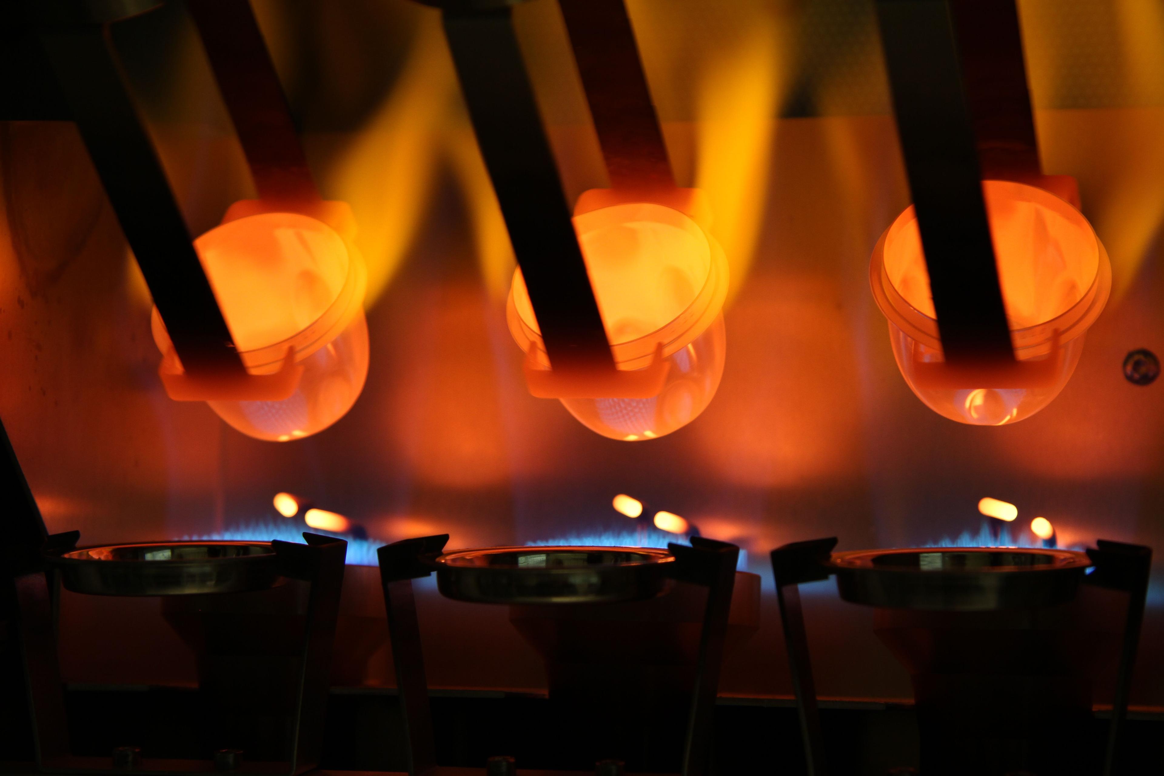 Flammer fra flere gassbrennere som varmer opp metall i smelteovner.