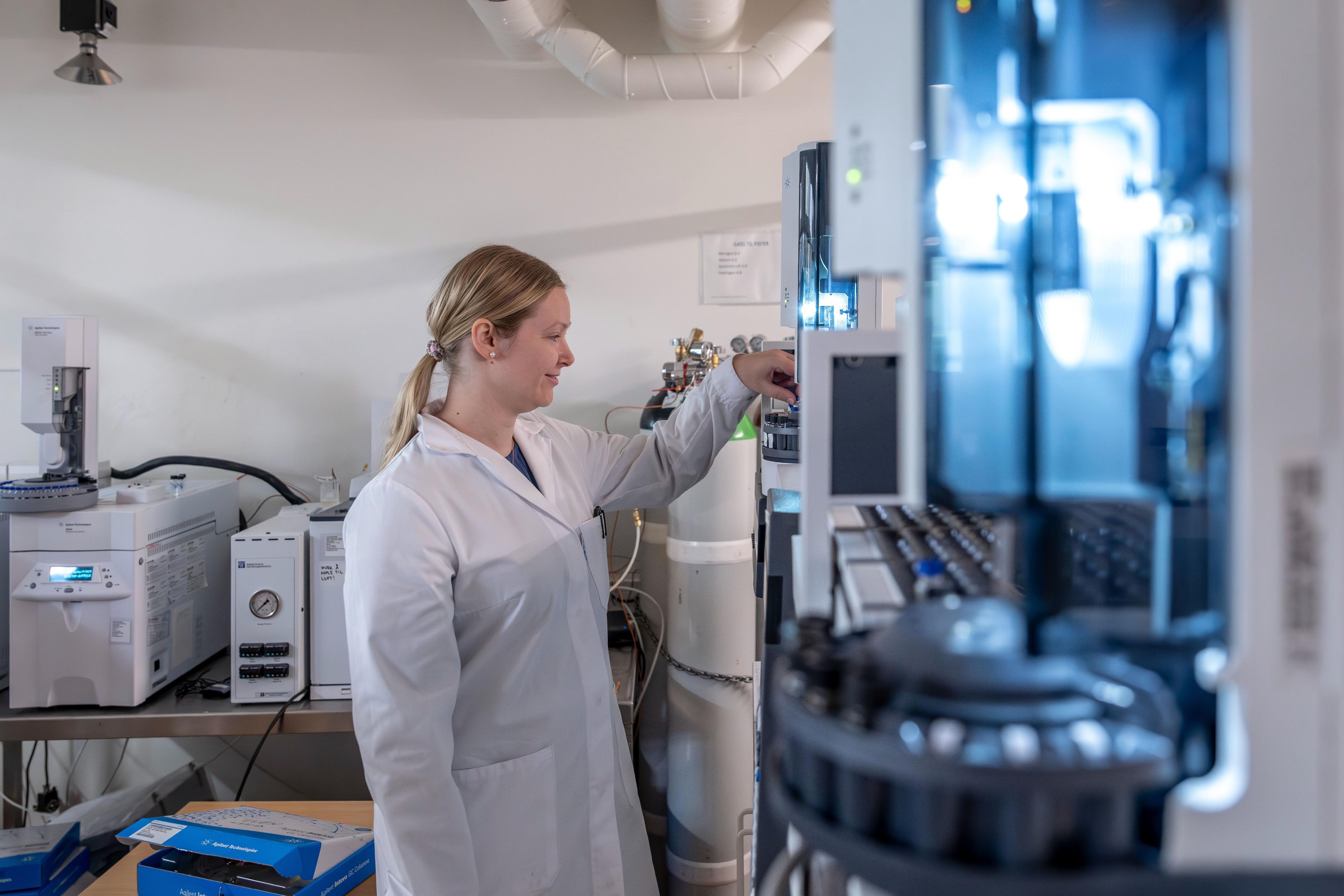 Kvinne i laboratoriefrakk som jobber med vitenskapelig utstyr i et moderne laboratorium.
