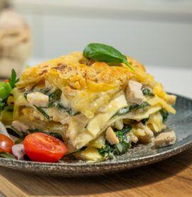 Lettvint lasagne med kylling, spinat og tomater servert på en grå tallerken.