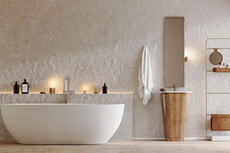 Moderne bad med et hvitt badekar, trevask og speil, samt dekorative lys og produkter på hyllen.