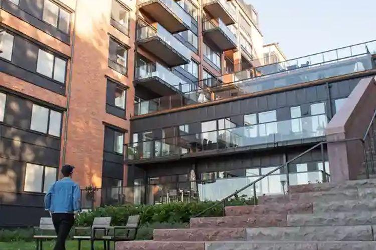 En person går mot en moderne leilighetsbygning med balkonger og store vinduer.