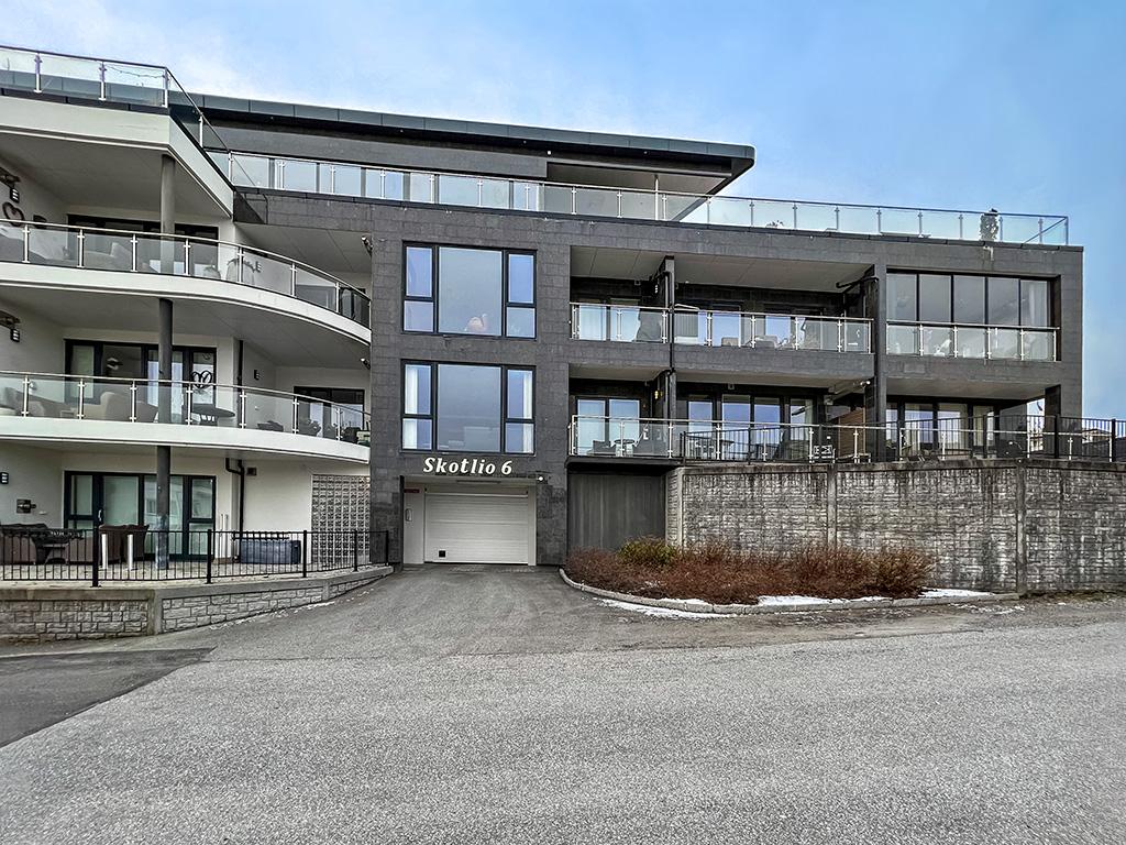 Moderne leilighetsbygg med balkonger og garasje, beliggende i et rolig område.