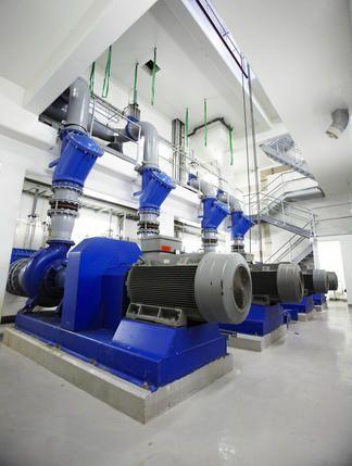 Moderne pumper og motorer i et industrielt anlegg med blå detaljer og rørledninger.