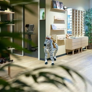 En zebrafigur står i en moderne butikk med trehyller og planter i bakgrunnen.