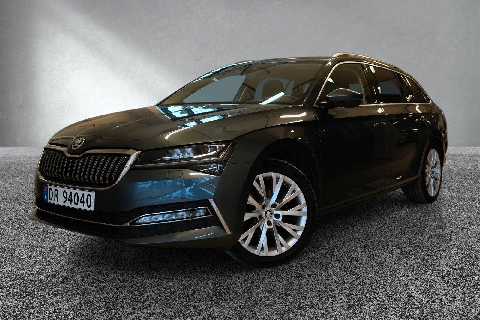 En svart Skoda Superb stasjonsvogn med moderne design og store felger, plassert på en grå bakgrunn.