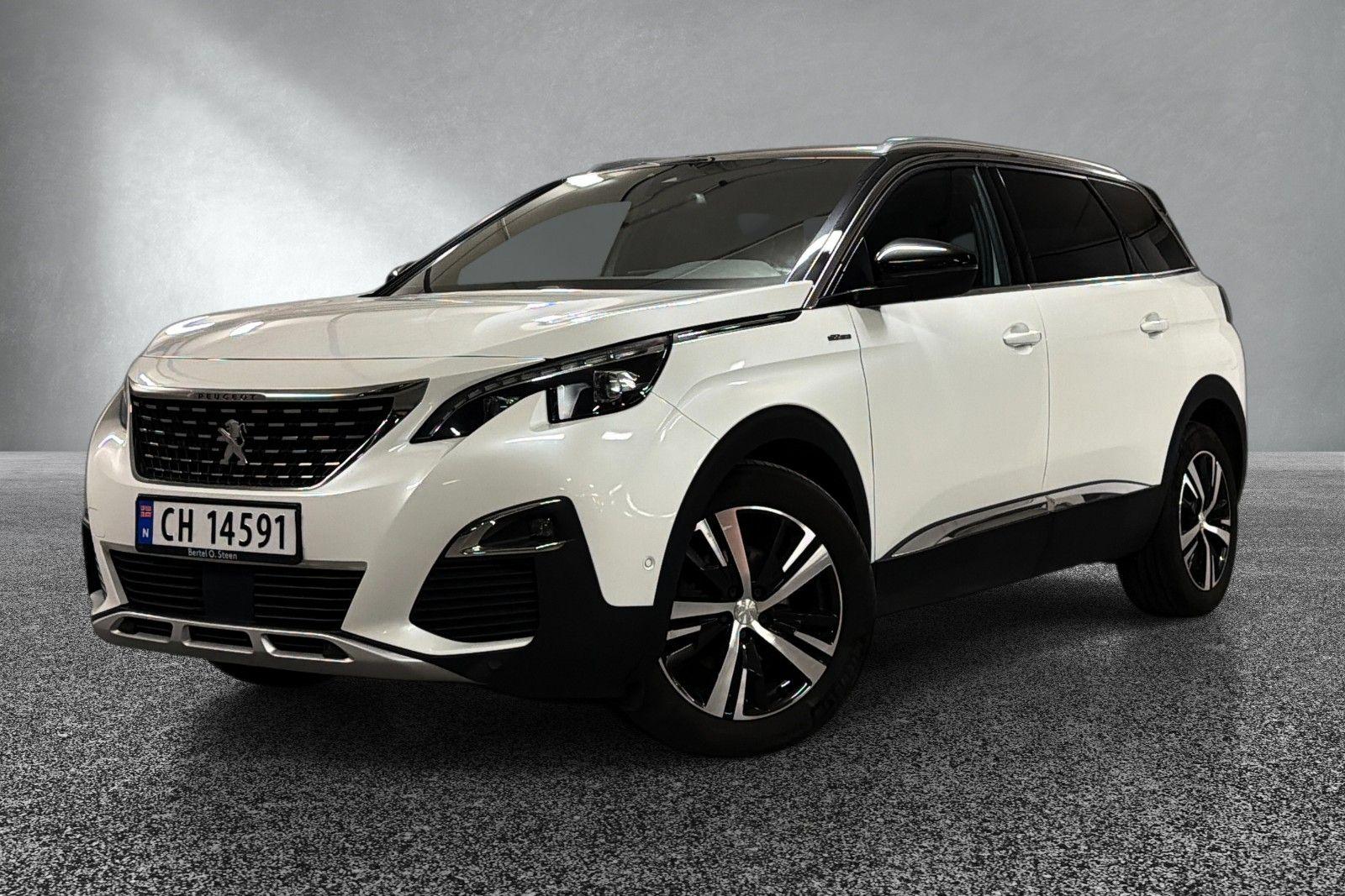 En hvit SUV fra Peugeot med moderne design og store felger, stående på en grå bakgrunn.