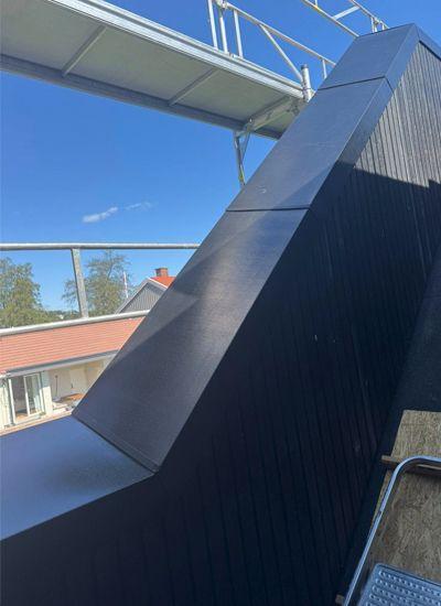 Moderne tak med skråning og rekkverk, under en klar blå himmel.