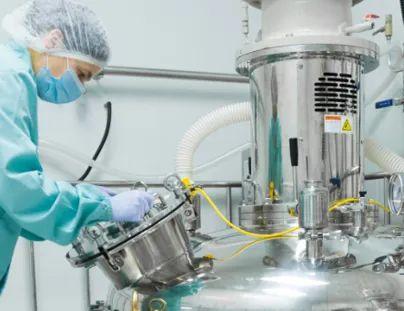 En tekniker i beskyttelsesutstyr arbeider med en stor, metallisk tank i et laboratorium.
