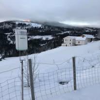 En snødekt landskap med en gård i bakgrunnen og en værstasjon i forgrunnen.