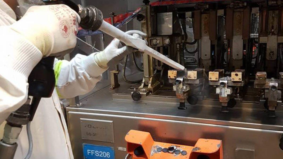 En person i hvit frakk bruker en pipette på en laboratoriemaskin med flere ventiler.