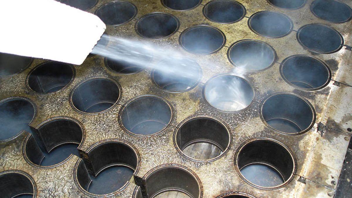 Sprayvann som påføres en metallform med runde hull for produksjon av kaker eller godteri.