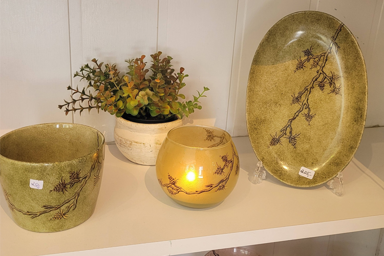 Dekorative keramikkvarer i grønt med blomsterdesign, inkludert en skål, lysestake og fat.