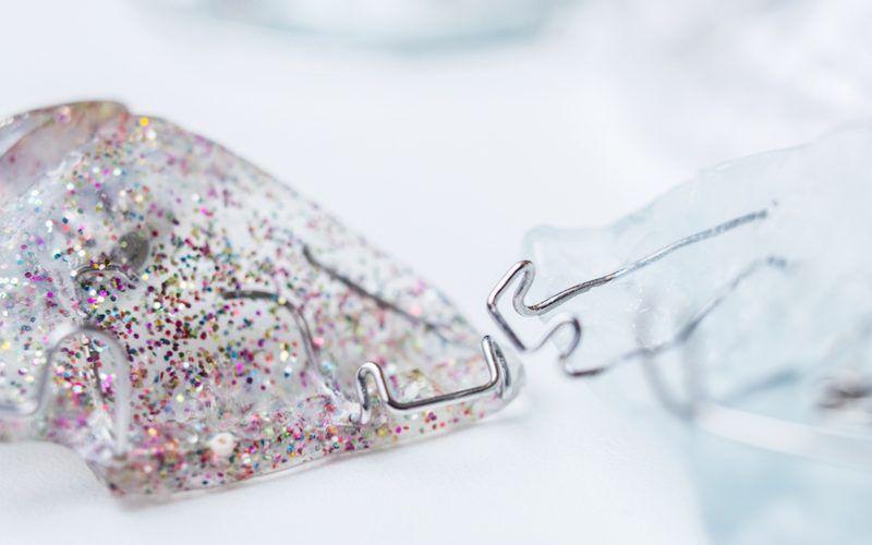 Glitrende plastbiter med glitter og en metallklips som holder dem sammen.