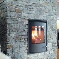 Moderne peis med glassdør i en steinvegg, som gir varme og koselig atmosfære i stuen.