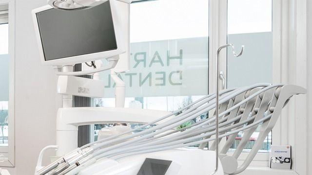 Moderne tannlegekontor med hvit tannlegestol og digitale skjermer i et lyst rom.