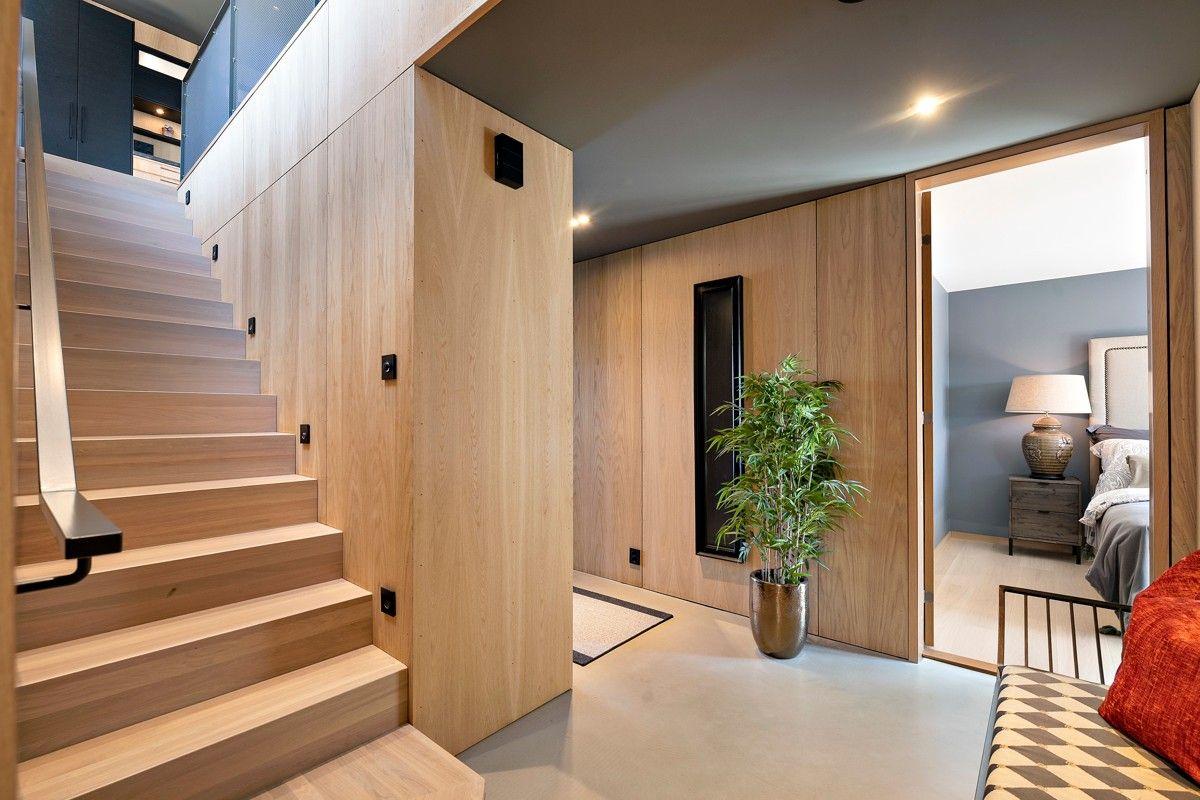 Moderne entré med tretrapp, grønne planter og stilige detaljer i et lyst rom.