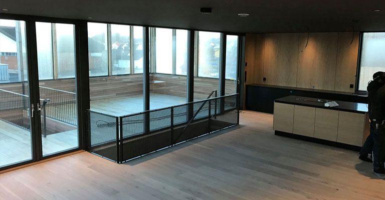 Moderne stue med store vinduer, trepanel og åpen planløsning mot en terrasse.