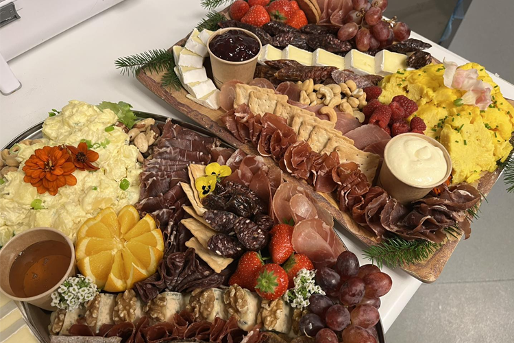 Et variert koldtbord med spekemat, oster, frukt, reker og salater, dekorert med urter og blomster.