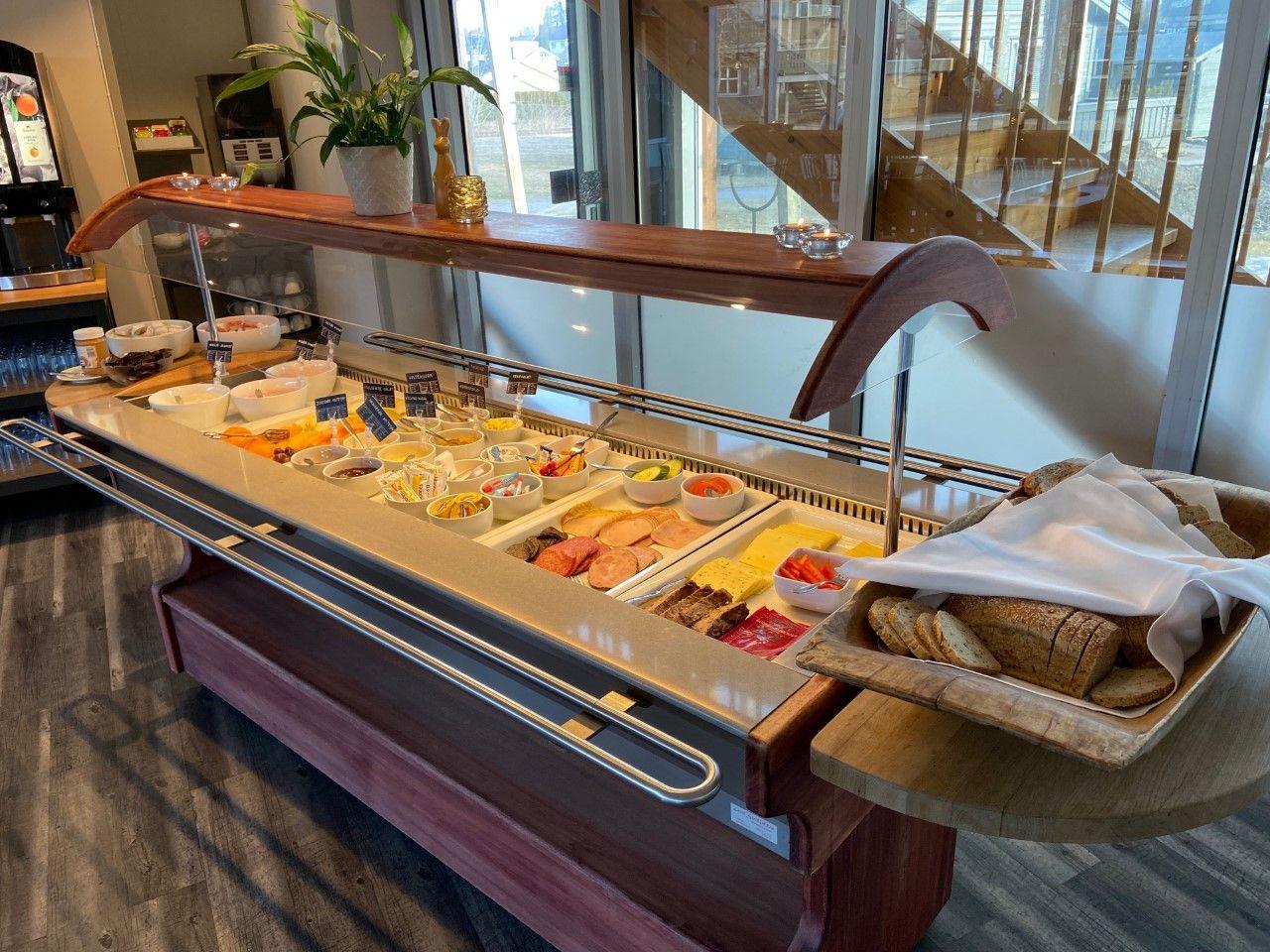 Frokostbuffet med variert utvalg av pålegg, brød og frukt i en moderne restaurant.