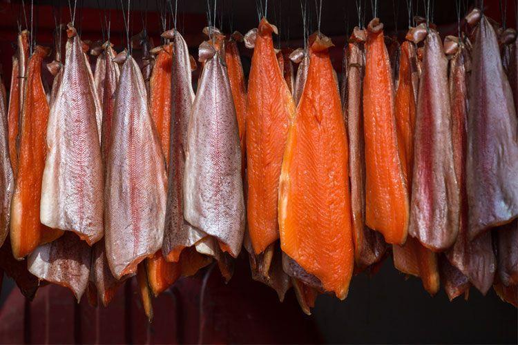 Røkt fisk henger til tørk, med varierte farger fra lys til mørk rød, på en tradisjonell fiskemarked.