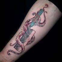 Tatovering av en kniv med en blekksprut som omfavner den, plassert på en arm.