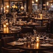 En koselig restaurant med mørk belysning, dekket bord med glass og stearinlys.