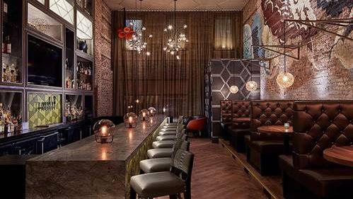 Stilig restaurantinteriør med en lang bar, komfortable sitteplasser og moderne belysning.