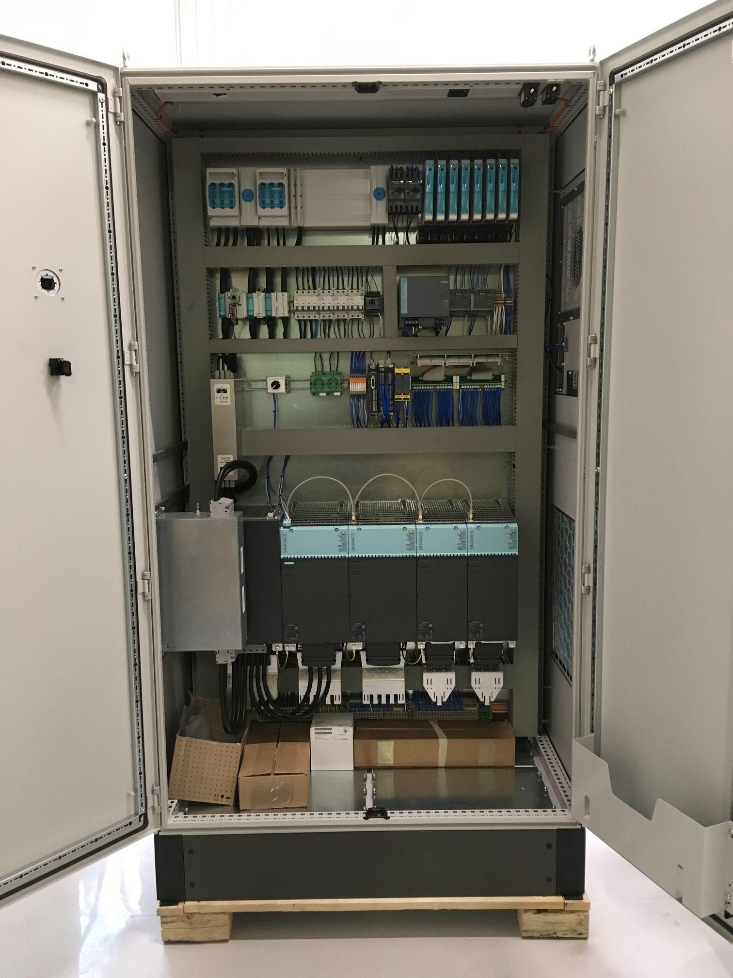 Skap med elektrisk utstyr og kabler, åpent for inspeksjon, med flere komponenter og tilkoblinger synlige.